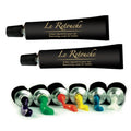 Two black tubes of 'Le Retouche' cream with colorful dabs on a white background